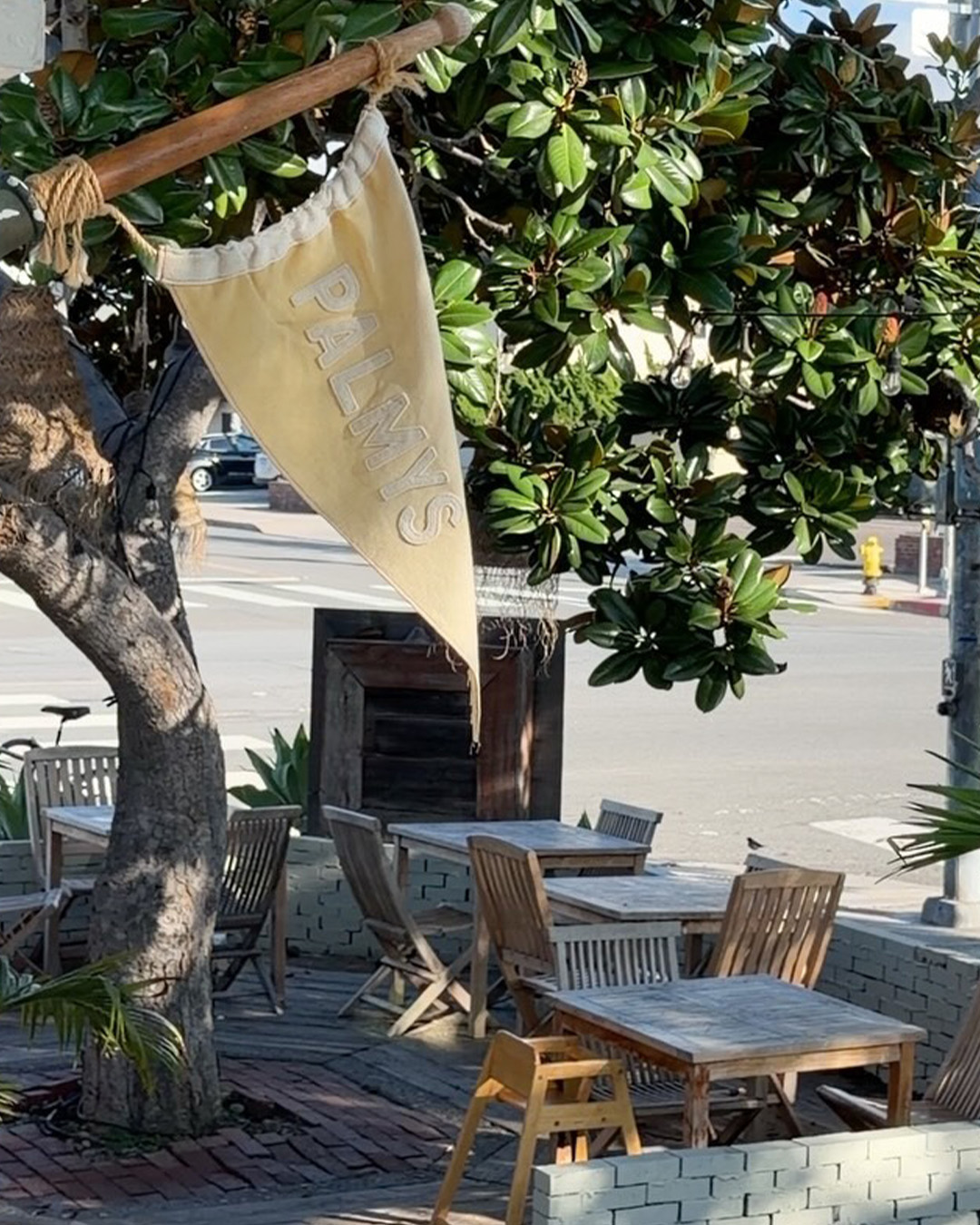 The Palmys pennant hanging over the street-side patio tables
